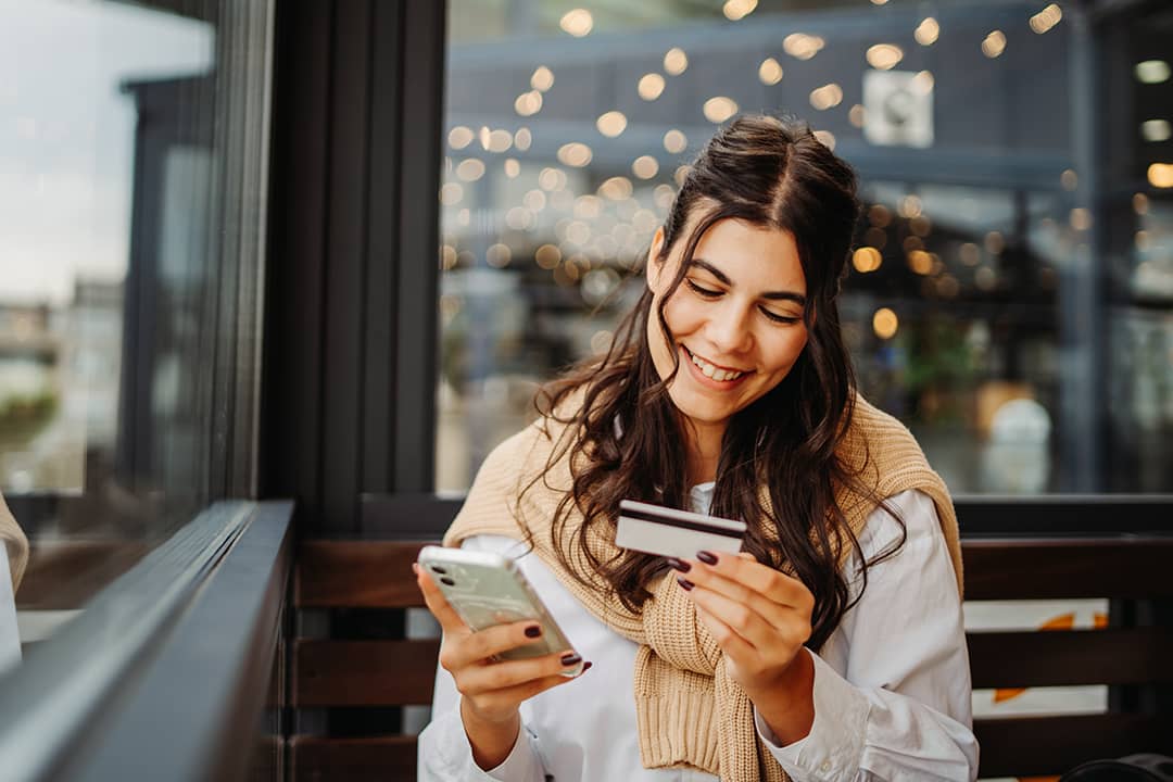 A happy young woman using a credit card to purchase online.